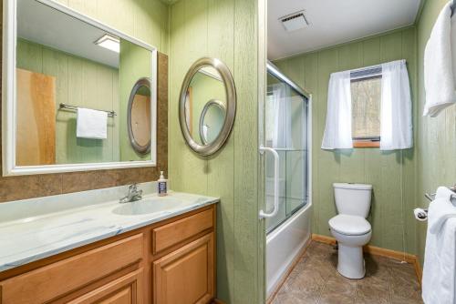 La salle de bains est pourvue d'un lavabo, de toilettes et d'un miroir. dans l'établissement Hot Tub, Big Deck, Comm Pool, WiFi at Chalet Cabin, à Berkeley Springs