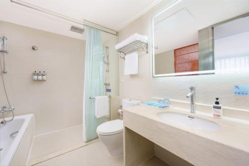 La salle de bains est pourvue d'un lavabo, de toilettes et d'un miroir. dans l'établissement Holiday Inn Express City Centre Dalian, an IHG Hotel, à Dalian