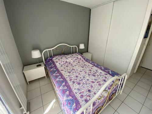 ein kleines Schlafzimmer mit einem Bett mit einer lila Decke in der Unterkunft Appartement Arcachon, 2 pièces, 3 personnes - FR-1-474-167 in Arcachon
