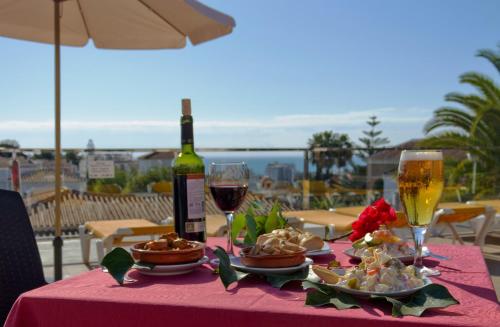 a table topped with plates of food and glasses of wine at Hotel Nerja Club Spa by Dorobe in Nerja