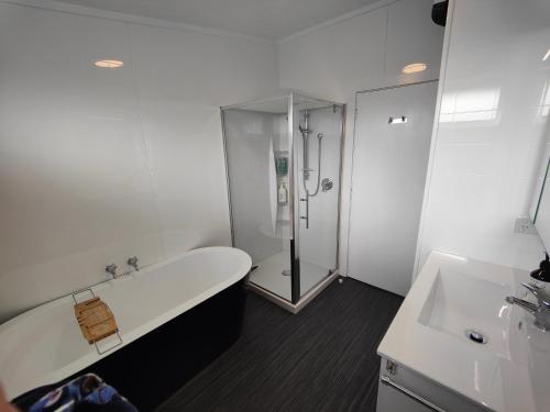 a white bathroom with a tub and a shower at A Family Favourite! in Riverton