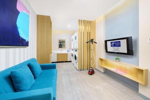 a living room with a blue couch and a tv at Holiday Inn Express City Centre Dalian by IHG in Dalian