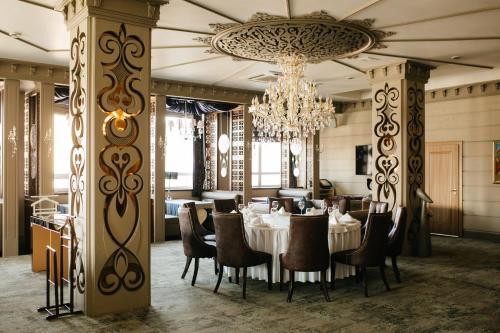 a dining room with a table and chairs and a chandelier at Jumbaktas Astana Hotel in Astana