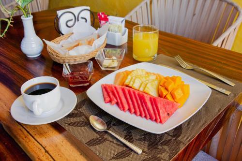 a table with a plate of fruit and a cup of coffee at Hotel Marionetas in Mérida