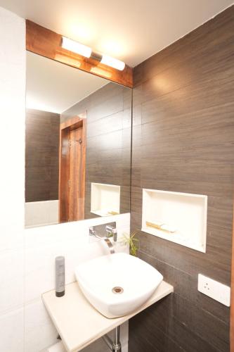 La salle de bains est pourvue d'un lavabo blanc et d'un miroir. dans l'établissement Hotel Hardeo, à Nagpur
