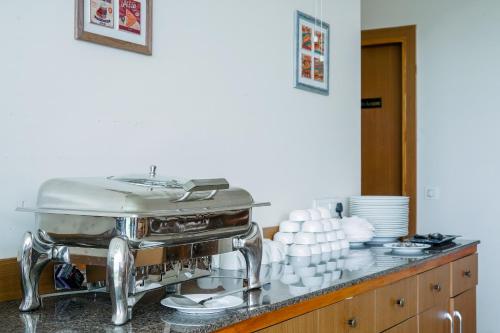 um balcão de cozinha com um grelhador com chávenas e pratos em Saltstayz Select - Unitech Cyber Park em Gurgaon