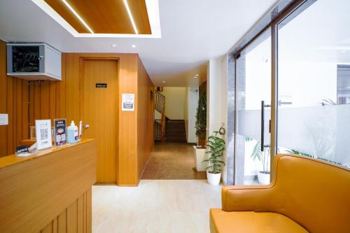 an office lobby with a yellow chair and a hallway at Saltstayz Grand Sky - Unitech Cyber Park in Gurgaon