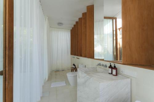 ein Badezimmer mit einem WC und einem Waschbecken mit einem Spiegel in der Unterkunft makali Temple Village in Canggu