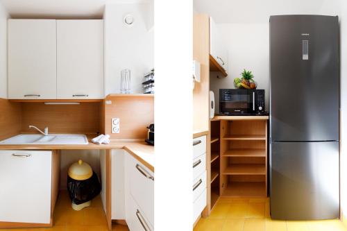 une cuisine avec des armoires blanches et un réfrigérateur en acier inoxydable dans l'établissement Les Liserons YourHostHelper, à Cannes