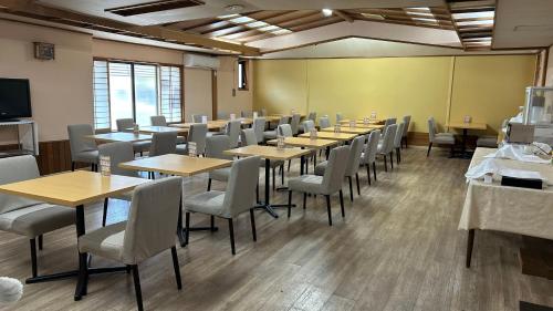 a conference room with tables and chairs and a screen at Hotel Tsukuba Hills Gakuen-odori in Tsukuba