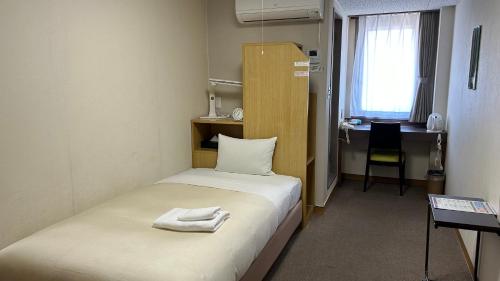 a small room with a bed with two towels on it at Hotel Tsukuba Hills Gakuen-odori in Tsukuba