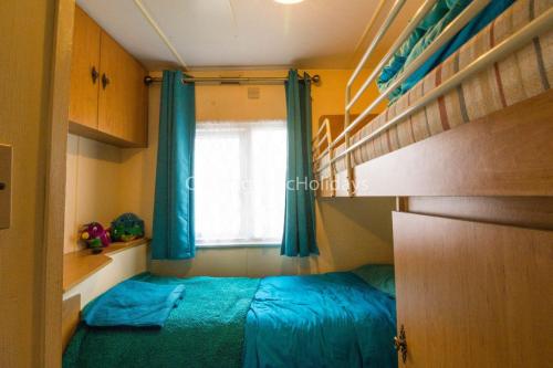 Schlafzimmer mit einem Bett, einem Fenster und Etagenbetten in der Unterkunft 8 Berth Dog Friendly Caravan In Summerfields Holiday In Norfolk Ref 19160s in Scratby