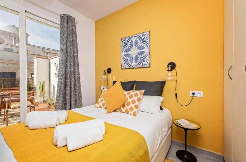 a bedroom with a bed with yellow walls and a window at Sweet Inn - Atic Gracia in Barcelona