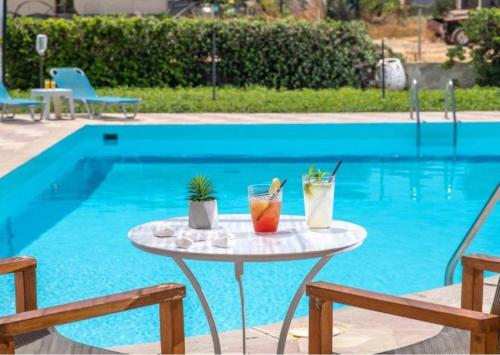 a table with drinks on it next to a swimming pool at Anemos Inn by Estia in Kokkíni Khánion