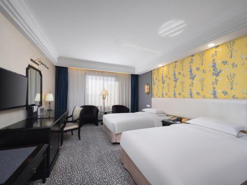 杭州市にあるグランド メトロパーク ホテル ハンヂョウのベッド2台とデスクが備わるホテルルームです。
