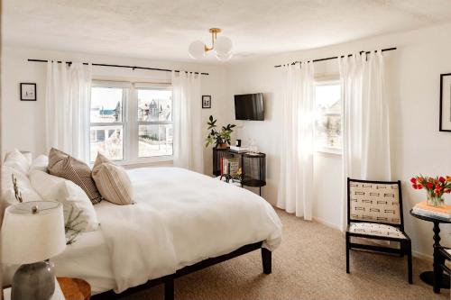 a bedroom with a large white bed and two windows at The Bentley Inn in Bay Head