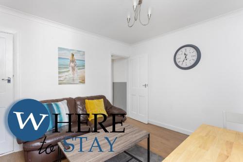 a living room with a couch and a clock on the wall at Entire Modern House City Center in Barrow in Furness