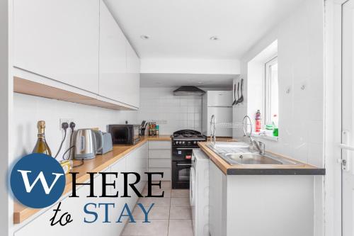 a kitchen with white cabinets and a sink with the words where to stay at Entire Modern House City Center in Barrow in Furness