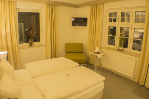 a hotel room with two beds and a chair at Garni Hotel Schmaus in Viechtach