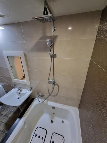 a bathroom with a bath tub and a sink at Fox Motel in Daegu