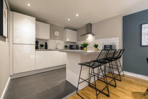 Host & Stay - Duke Street Abode في ليفربول: مطبخ مع خزائن بيضاء وكراسي البار الأسود
