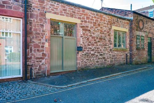 a brick building with a green door and two windows at Host & Stay - The Georgian Coach House 1 in Liverpool