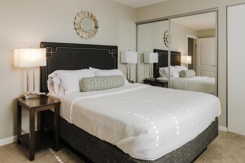ein Schlafzimmer mit einem großen weißen Bett und einem Spiegel in der Unterkunft Modern Mass Ave 1BR Apartment with Kitchen in Indianapolis