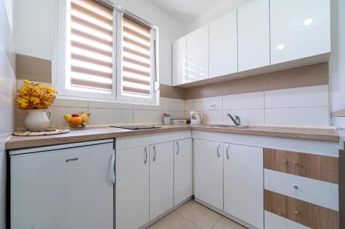 a white kitchen with white cabinets and a sink at Apartments Gruda in Cetinje
