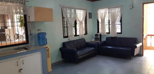 a living room with two leather chairs and windows at Sandra's holiday house in Oslob
