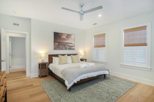 a white bedroom with a bed and two windows at Twin Palms Beach Old Village 5-Min to Dwntwn in Charleston