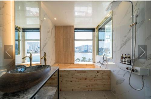 uma casa de banho com um lavatório de madeira e uma grande janela em De Homme Hotel em Busan