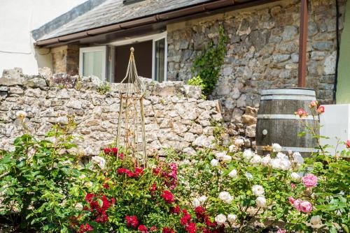 a stone house with a stone wall and flowers at Hideaway Cottages - Greenacres Estates in Tenby