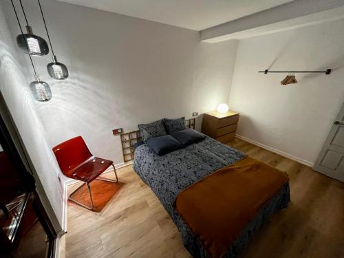 1 dormitorio con 1 cama y 1 silla roja en Loft Villaviciosa, en Villaviciosa