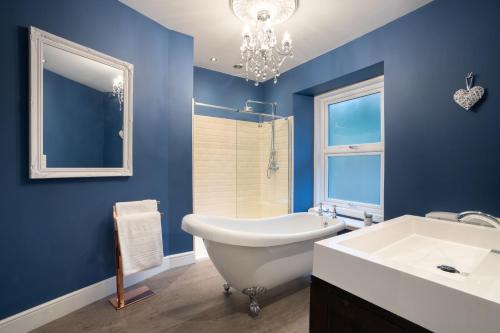 ein blaues Badezimmer mit einer weißen Badewanne und einem Waschbecken in der Unterkunft Spacious Home with Outstanding Views by LetMeStay in Ambleside