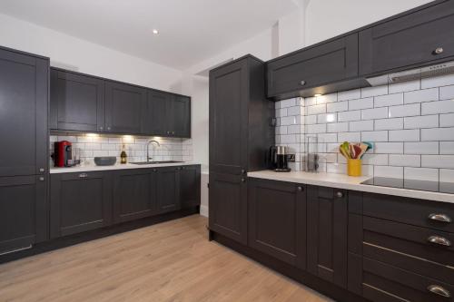 a large kitchen with black cabinets and white tiles at Spacious Apartment in Coniston, by LetMeStay in Coniston