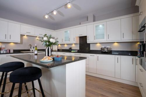 a kitchen with white cabinets and a counter with stools at Brand New - Contemporary - 2 Bedroom - 2 Bathroom - Spacious Apartment - Lake Views in Ambleside
