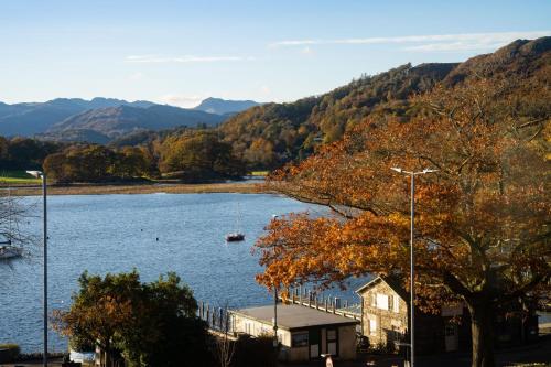 a lake with a house and a boat in the water at Brand New - Contemporary - 2 Bedroom - 2 Bathroom - Spacious Apartment - Lake Views in Ambleside