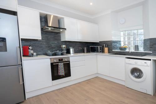 a kitchen with white cabinets and a washer and dryer at Redbanks Apartment in Ambleside
