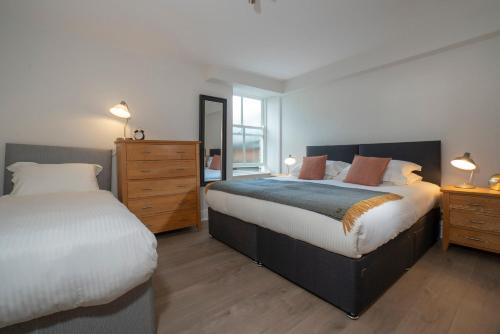 a bedroom with two beds and a dresser at Redbanks Apartment in Ambleside