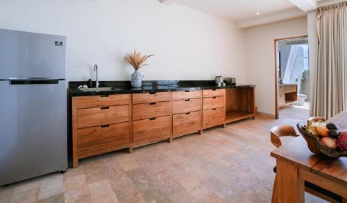 a kitchen with wooden cabinets and a stainless steel refrigerator at Sumberkima Resort in Pemuteran