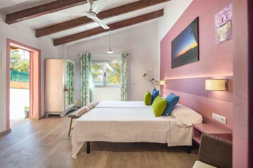 Un dormitorio con una cama grande y una pared rosa en Finca Can Marti, en Alcudia