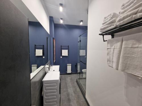 La salle de bains est pourvue d'un lavabo et d'un mur bleu. dans l'établissement Apart Hotel LOFT, à Almaty