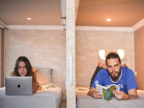 a man and a woman laying on a bed with a laptop at La Zona Hostel in San Salvador