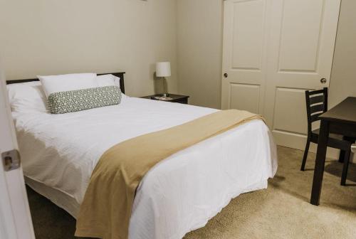 a bedroom with a white bed with a pillow and a table at Vibrant 2BR Corner Suite and Free Parking at CityWay in Indianapolis