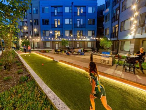 a woman walking through a park in front of a building at Vibrant 2BR Corner Suite and Free Parking at CityWay in Indianapolis