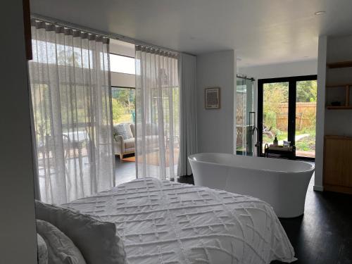 a bedroom with a tub and a bed and a room with a view at Shibui Lilydale Luxury Romance in Lilydale