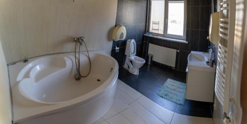 a bathroom with a large tub and a toilet at Romainiai guest house in Kaunas