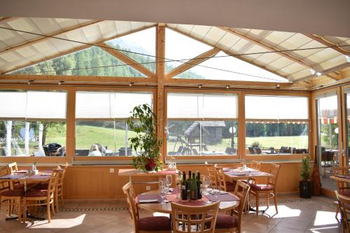 un comedor con mesas, sillas y ventanas en Restaurant & Hostel Hole in One en Randa