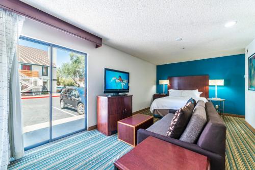 a hotel room with a bed and a couch and a tv at Metro PHX STUDIO QUEEN UPSTAIRS sleeps 4 modern design best amenities in Phoenix