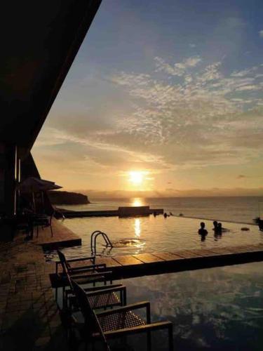 a swimming pool with the sun setting over the ocean at Suite Exclusiva frente al mar Hotel Poseidón Manta in Manta